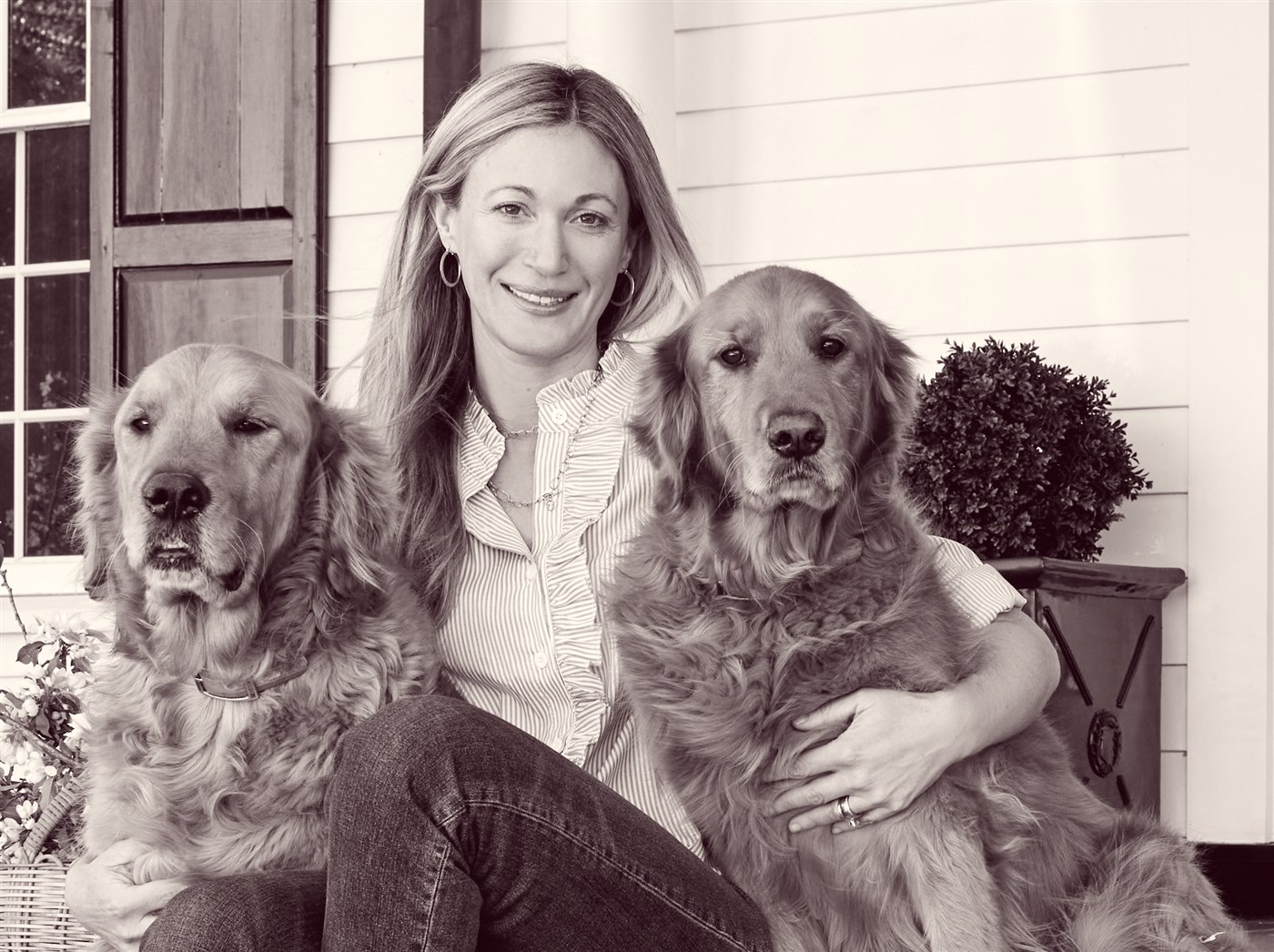 Carmel Greer with her two golden retrievers on the front porch